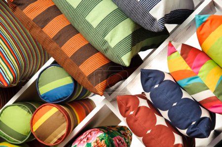 Set of various colorful pillows with different patterns and sizes, on a shelf