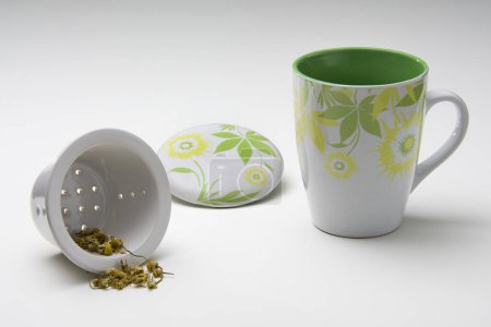 Kit of ceramic mug, infuser and a lid, with a flower illustration, isolated
