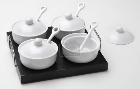Foto de Kit de cuatro ollas de cerámica blanca con cucharas, aisladas en blanco - Imagen libre de derechos
