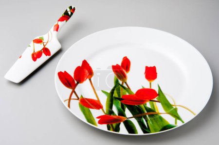 Photo for Kit with round cake plate and cake shovel, with red tulip print, isolated - Royalty Free Image
