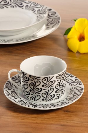 Kaffeetasse-Set mit Untertasse auf einem Holztisch mit Geschirr im Hintergrund