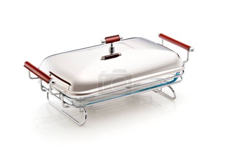 A chafing dish isolated in a white background. A metal serving pan on a stand with an alcohol burner holding chafing fuel below it. It is used as a food warmer for keeping dishes at a buffet warm. 