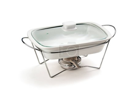 A ceramic or porcelain chafing dish isolated in a white background. A serving pan on a stand with an alcohol burner below it. It is used as a food warmer for keeping dishes at a buffet warm. 