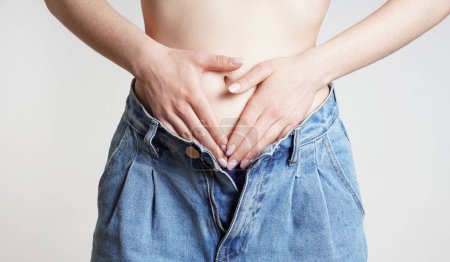 Téléchargez les photos : Femme en jeans mains tenant le ventre avec douleurs abdominales ou menstruelles - en image libre de droit
