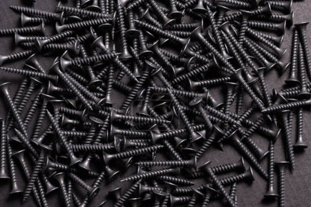 Foto de Metal, tornillos autorroscantes de acero inoxidable en respaldo de madera negro - Imagen libre de derechos