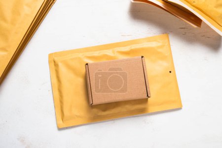 Kartonschachtel und gepolsterter Bubble Mailer auf weißer Holztischplatte