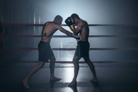 Photo for Two shirtless muscular man fighting Kick boxing combat in boxing ring. High quality photo - Royalty Free Image