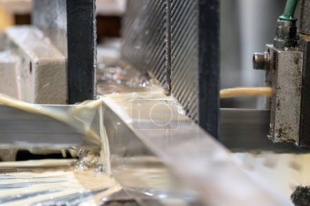 Automatische Bandsägemaschine, die die Metallstange mit Kühlwasserbasis schneidet. Hochwertige Fotografie