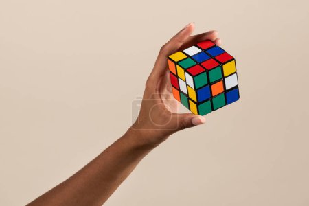 Photo for Crop hand of black woman demonstrating unsolved brain teaser of Rubik cube on beige background - Royalty Free Image