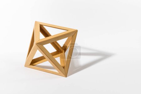 Foto de Forma de octaedro sólido platónico hecho de piezas de madera que proyectan sombra sobre fondo gris - Imagen libre de derechos