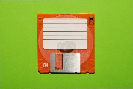 Téléchargez les photos : Vue du dessus du papier vierge avec des lignes collées sur disquette brune sur fond vert - en image libre de droit