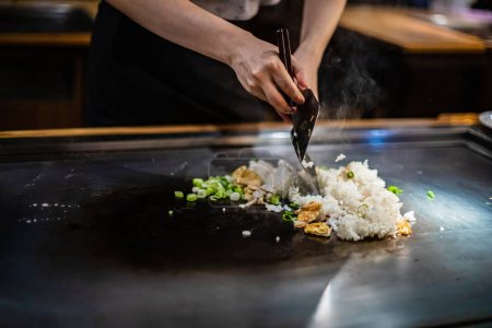 Téléchargez les photos : Teppanyaki, Japanese Cooking teppan show dans un restaurant japonais traditionnel. les mains du cuisinier. Le cuisinier japonais prépare viande, poisson, riz, légumes sur la table chaude - en image libre de droit