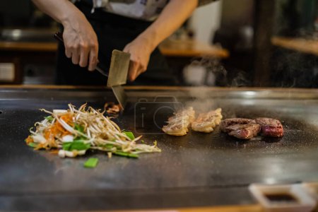 Teppanyaki, Japanese Cooking teppan show dans un restaurant japonais traditionnel. les mains du cuisinier. Le cuisinier japonais prépare viande, poisson, riz, légumes sur la table chaude