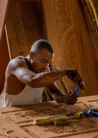 Foto de Stone Town, Zanzíbar, Tanzania. 27 de marzo de 2018. Maestro tallador de madera en el trabajo. virutas de madera, ranuras y cinceles en el banco de trabajo. De cerca. las manos del maestro en el trabajo - Imagen libre de derechos