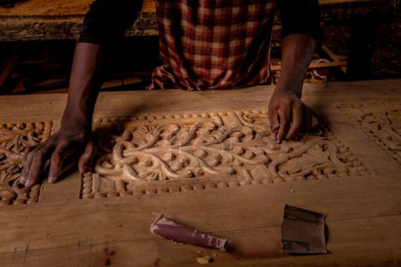 Foto de Stone Town, Zanzíbar, Tanzania. 27 de marzo de 2018. Maestro tallador de madera en el trabajo. virutas de madera, ranuras y cinceles en el banco de trabajo. De cerca. las manos del maestro en el trabajo - Imagen libre de derechos