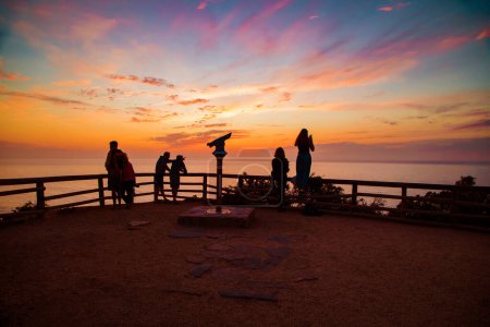 Foto de Arrifana, Aljezur, Portugal. Silueta de personas mirando una puesta de sol naranja profunda.Concepto de viaje y naturaleza - Imagen libre de derechos