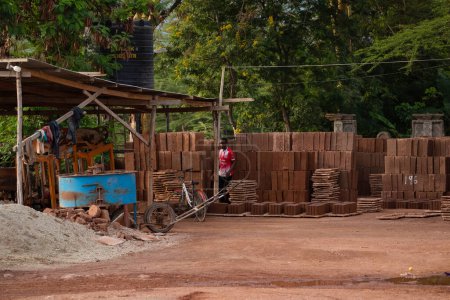Téléchargez les photos : Arusha, Tanzanie, Afrique. 04 février 2022.vie dans un village africain. une petite usine privée de briques en Afrique. Un travailleur se tient près d'un chariot et d'un grand tas de briques - en image libre de droit