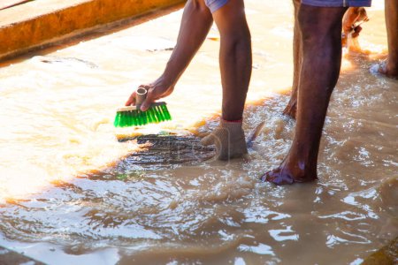 Foto de Trabajadores irreconocibles en una pequeña fábrica de pescado en Sri Lanka lavan pescado de atún filete en agua fangosa y sucia con sus pies en ella. - Imagen libre de derechos