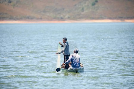 Foto de Montasoa, Madagascar 08.10.2023. dos pescadores en un pequeño barco en el lago lanzan una red para pescar - Imagen libre de derechos