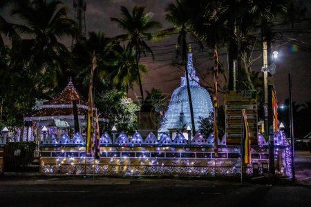 Foto de Kalutara, Sri Lanka, 10.02.2023 Estupa tradicional del templo blanco de Sri Lanka iluminada con luces por la noche. estupa festivamente decorada - Imagen libre de derechos