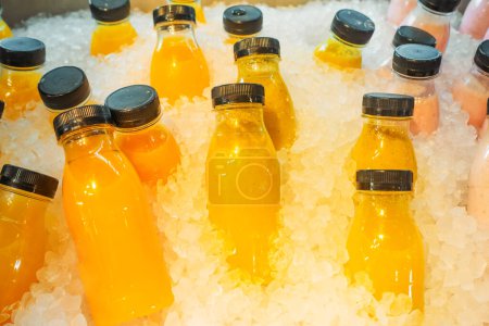 Healthy fresh juice freeze in ice. several plastic bottles of juice stand cooling in ice, ready for sale