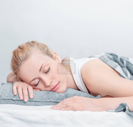 Photo for A beautiful young woman lying on a pillow, gazing at the camera with a gentle smile. Capturing a moment of tranquility and natural beauty for lifestyle or wellness concepts. - Royalty Free Image