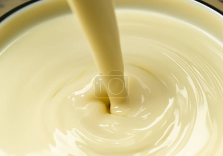 Téléchargez les photos : Verser du chocolat blanc au lait liquide fondu de qualité supérieure - en image libre de droit