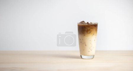 Iced latte coffee on wooden table, white background. Cold beverage in summer.
