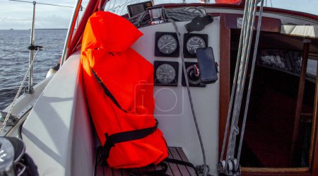 Eine Schwimmweste liegt auf einem modernen Boot neben dem Navigationssystem. Modernes Boot. Bootsfahrt. Segeljacht mit Navigationssystem. Hochwertiges Foto