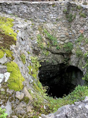 Antiguo muro de piedra y musgo verde en la entrada de la cueva.
