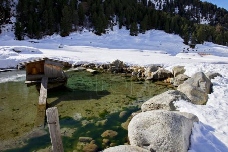 Teich mit Steinen und Schnee in einer Winterlandschaft