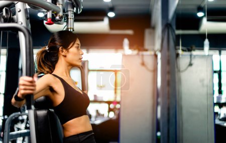 Foto de Ejercite sus brazos con esta máquina de ejercicios de brazo. ejercicio saludable de las mujeres en gimnasio de fitness - Imagen libre de derechos
