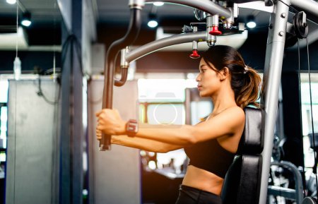 Foto de Ejercite sus brazos con esta máquina de ejercicios de brazo. ejercicio saludable de las mujeres en gimnasio de fitness - Imagen libre de derechos