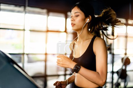 Foto de Correr con una cinta de correr ejercitarse en el gimnasio alegría de correr escuchar música mientras se ejecuta el ejercicio de concepto de proceso de cuidado de la salud de las mujeres jóvenes - Imagen libre de derechos