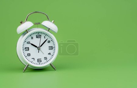 Photo for White alarm clock tells time working with time importance of time punctuality White clock on a green background - Royalty Free Image