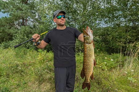 Téléchargez les photos : Pêche au brochet réussie. heureux pêcheur tenir muskie poisson - en image libre de droit
