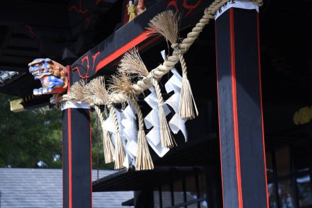 Photo for 'Shimenawa' ( Shinto straw festoon ) in the japanese shrine. Shimenawa consists of a rice-straw rope and white paper cut in stripes. It is considered a barrier against evil spirits. - Royalty Free Image