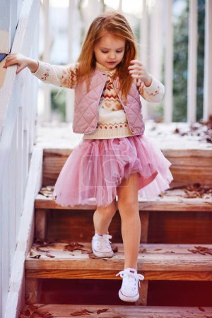 Téléchargez les photos : Pretty little baby girl going down the stairs. Girl's fashion. Tutu skirt - en image libre de droit