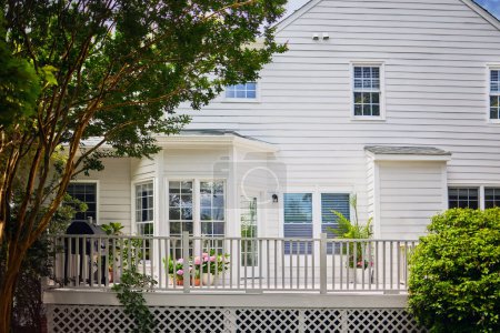 Foto de Casa tradicional con terraza de madera blanca en el jardín en el día de verano - Imagen libre de derechos