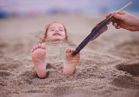 Photo for Tickling happy baby's feet in a sand. family having fun on sandy beach. summer activity. coastal vacation - Royalty Free Image