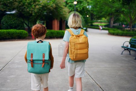 Téléchargez les photos : Vue arrière des enfants avec sacs à dos marchant de l'école - en image libre de droit