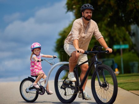 Téléchargez les photos : Père et fille, jeune enfant faisant du vélo ensemble. balade à vélo avec remorque à vélo remorquable. mode de vie actif pour les familles avec enfants - en image libre de droit