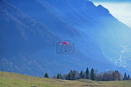 Téléchargez les photos : Un parapente décollant au-dessus d'une vallée avec une toile de fond spectaculaire de montagnes - en image libre de droit