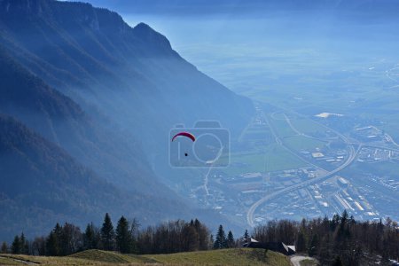 Téléchargez les photos : Un parapente décollant au-dessus d'une vallée avec une toile de fond spectaculaire de montagnes - en image libre de droit