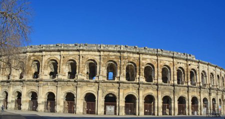 Foto de Arcos en la pared exterior del Anfiteatro Romano Antiguo en Nimes, en el sur de Francia. Uno de los anfiteatros mejor conservados del mundo - Imagen libre de derechos