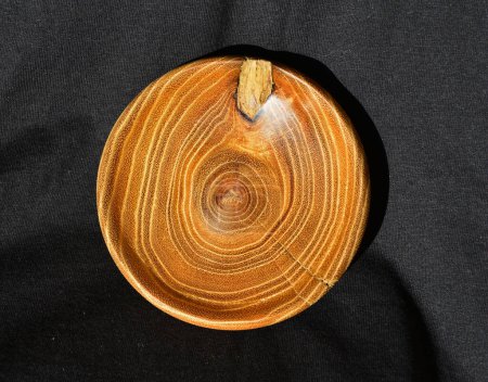 Foto de Decoración de cuenco de acacia vuelta manualmente de madera de acacia, contra un paño negro - Imagen libre de derechos