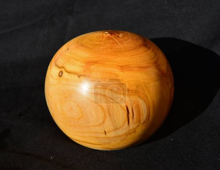 Foto de Decoración esfera de madera vuelta de madera de albaricoque, contra un paño negro - Imagen libre de derechos