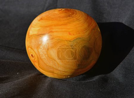 Foto de Decoración esfera de madera vuelta de madera de albaricoque, contra un paño negro - Imagen libre de derechos