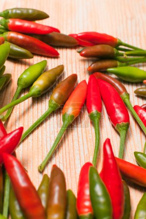 many small chili peppers on wooden background