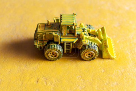 Photo for Dark yellow toy bulldozer on yellow background - Royalty Free Image